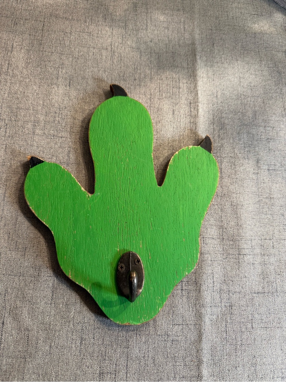 Mounted hook shaped like a green dinosaur like footprint, paw or claw. Boys room
